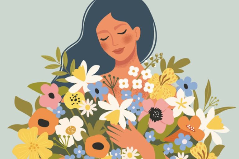 Smilende kvinde med lukkede øjne og favnen fuld af farverige blomster – et billede på styrke, eftertænksomhed og forandring i overgangsalderen.